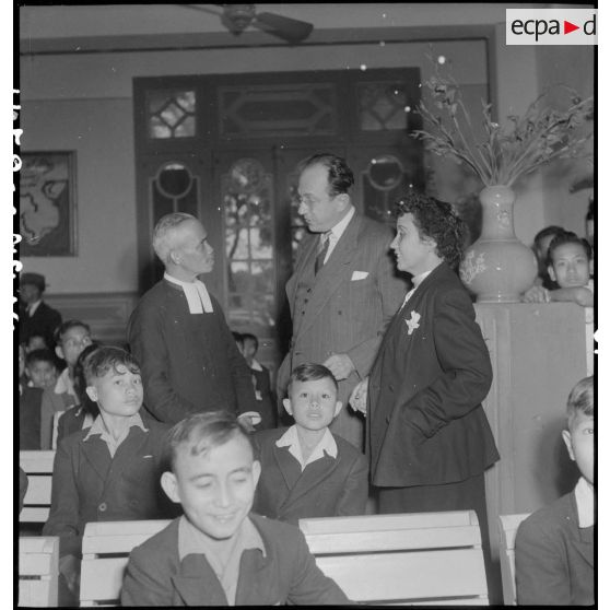 Distribution de jouets à l'AFOM : M. Mayet converse avec un Frère des écoles chrétiennes qui accompagne les jeunes à la fête.<br>