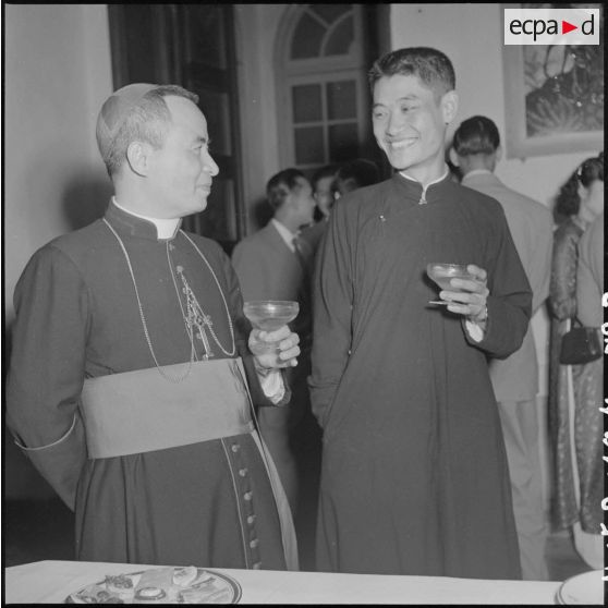 Mgr Trinh Nhu Khue, évêque d'Hanoï, et un jeune religieux vietnamien à la réception organisée pour la remise des insignes impériaux vietnamiens au chef de l'Etat du Vietnam M. Bao Dai par le général de Linarès.