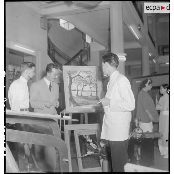 Guy Le Guillerm et deux hommes regardent un tableau lors du vernissage de l'exposition de peintures Dat -Le Guillerm.