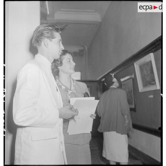 Un des artistes et une femme en civil à l'exposition de peintures Dat -Le Guillerm.