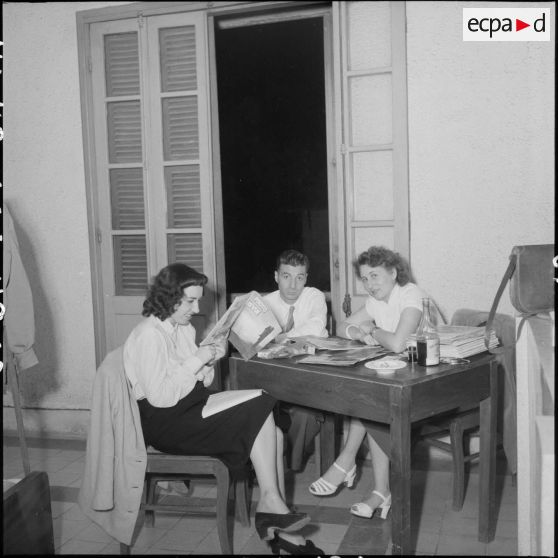 Raymond Varoqui et deux jeunes femmes autour d'une table au cours du bal annuel de la Croix-Rouge.