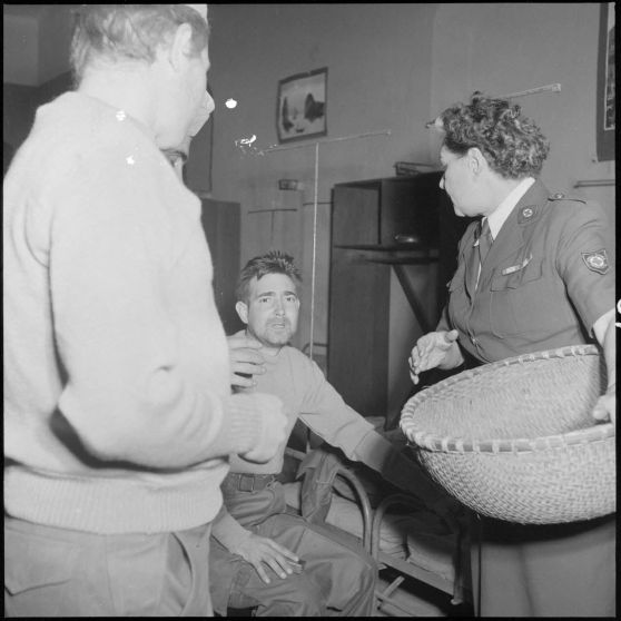 Une discussion entre des hommes du CEFEO (Corps expéditionnaire français en Extrême-Orient), récemment libérés, et une femme de la Croix-Rouge.	