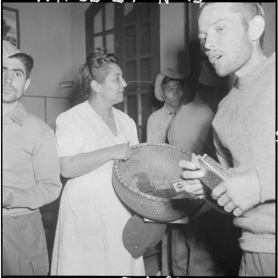 Une femme distribue des paquets de cigarettes aux hommes du CEFEO (Corps expéditionnaire français en Extrême-Orient) récemment libérés.