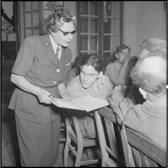 Une femme de la Croix-Rouge montre un cahier à un homme du CEFEO (Corps expéditionnaire français en Extrême-Orient) récemment libéré.