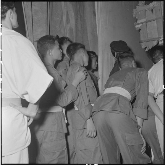 Dans les coulisses, de jeunes vietnamiens observent une démonstration de sports de combat au théâtre municipal d'Hanoï.