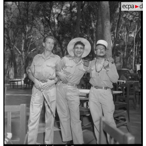 Deux permissionnaires posent pour une photographie de groupe avec l'aumônier militaire Deives.