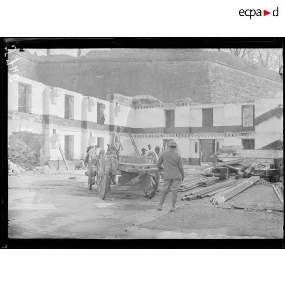 [Soldats chargeant du bois, dans une cour au pied d'un rempart.]