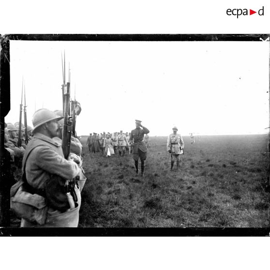 Le roi et la reine des Belges passant en revue la 1re DI de la 1re armée sur le champ d'aviation de Saint-Pol-sur-Mer. [légende d'origine]