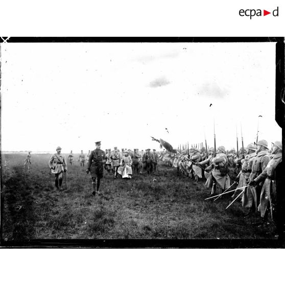 Le roi et la reine des Belges passant en revue la 1re DI de la 1re armée sur le champ d'aviation de Saint-Pol-sur-Mer. [légende d'origine]