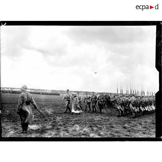 La reine des Belges, accompagnée du général Anthoine, passe sur le front des troupes de la 1re DI sur le champ d'aviation de Saint-Pol-sur-Mer. [légende d'origine]