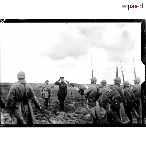 Le roi des Belges saluant le drapeau d'un régiment d'infanterie de la 1re DI, sur le champ d'aviation de Saint-Pol-sur-Mer. [légende d'origine]