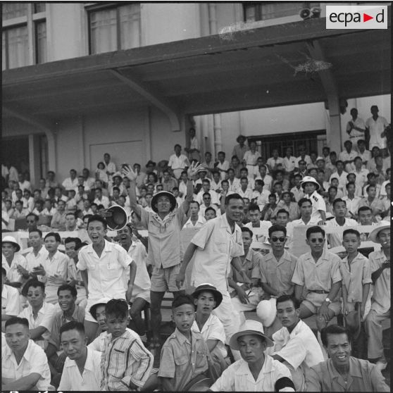 Dans les gradins du stade Mangin, les spectateurs s'enthousiasment pour le match de football opposant l'équipe de Nam-Hoa à la sélection Nord-Vietnam.