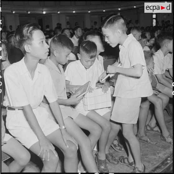 Au théâtre municipal d'Hanoï, de jeunes élèves du lycée Albert Sarraut comparent leurs prix.