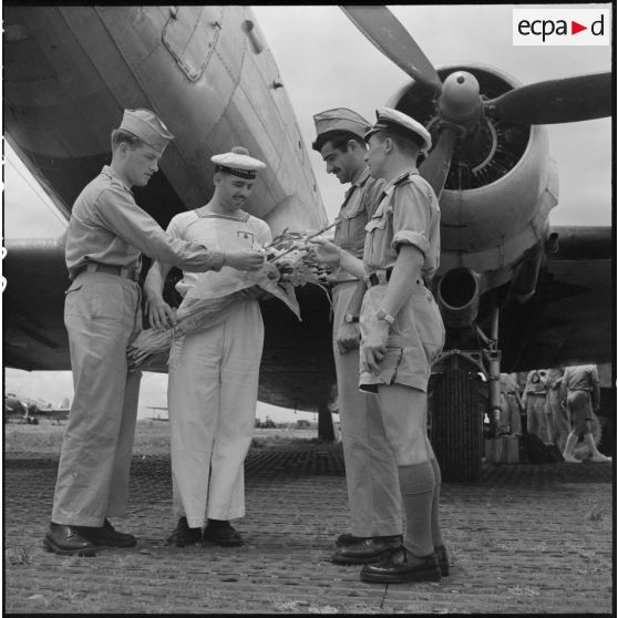 Militaires du rang et officier de l'armée de l'Air regardant un bouquet de fleurs tenu par un marin.