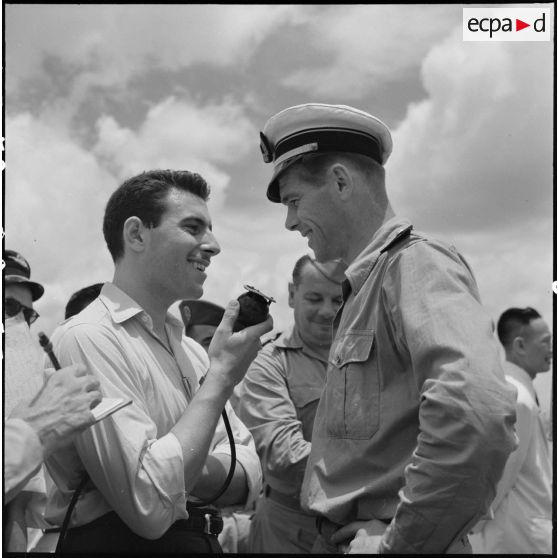 Dès son arrivée à l'aéroport de Gia Lam, un officier de l'armée de l'Air, dirigeant de l'équipe militaire de football de France, est interviewé par un reporter radio.