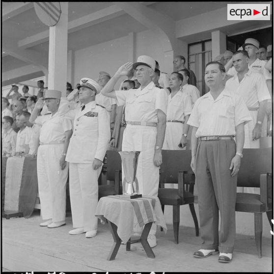 Dans la tribune officielle, les personnalités civiles et militaires saluent les hymnes nationaux.