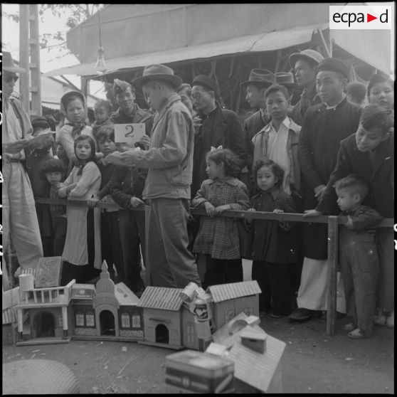 Des personnes devant un stand de la kermesse organisée au profit des invalides et des blessés de guerre d'Hanoï.