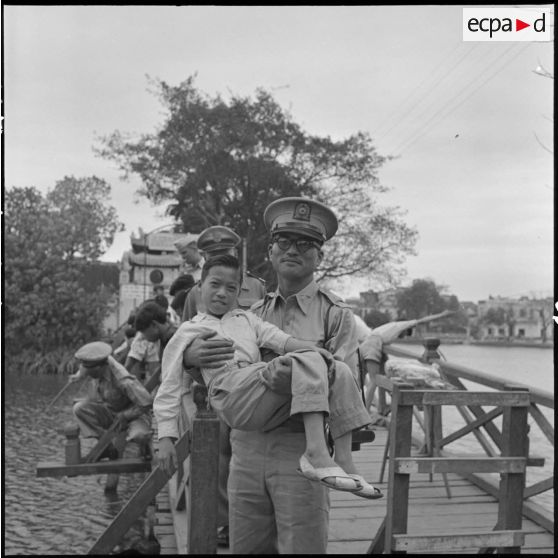 Officier coréen portant un enfant sur un pont du lac Hoan Kiem.