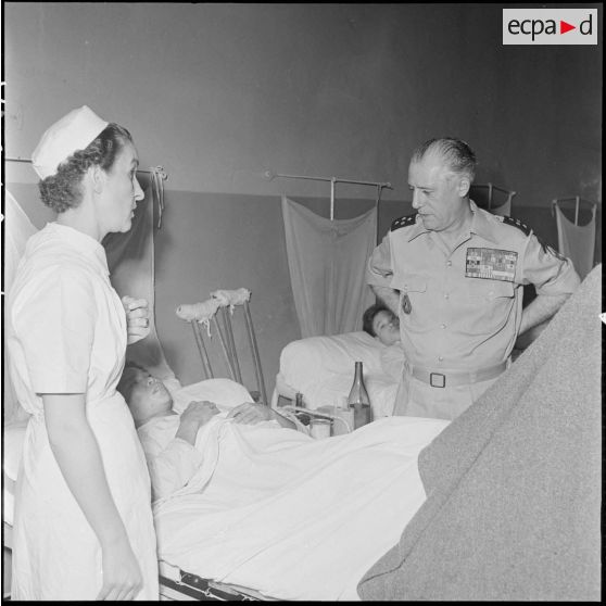 Le général Salan et une infirmière de  l'hôpital militaire Lanessan au chevet du lit d'un blessé.