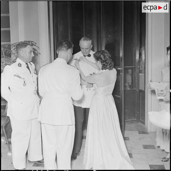 Vendeuse décorant le général Linarès d'un brin de muguet pour une soirée dansante organisée à l'hôtel Splendid.