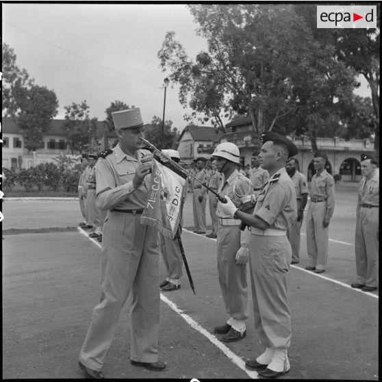 Le général Cogny, commandant en chef des FTNV (forces terrestres du Nord-Vietnam), décore le fanion du 71e CCR (compagnie de circulation routière).