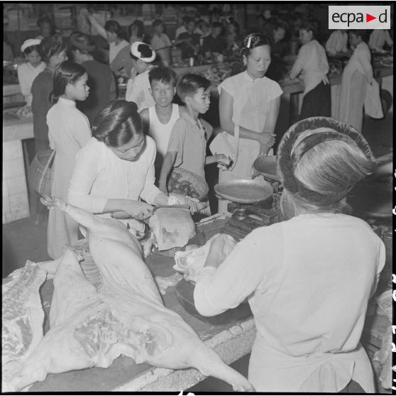 Au grand marché d'Hanoï, une charcutière coupe sa marchandise à son étal.