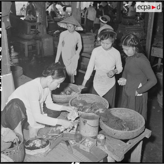 Au grand marché d'Hanoï, une commerçante compte des billets sur son étal.