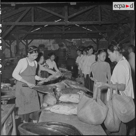 Une poissonnière débite sa marchandise devant ses clientes au grand marché d'Hanoï.