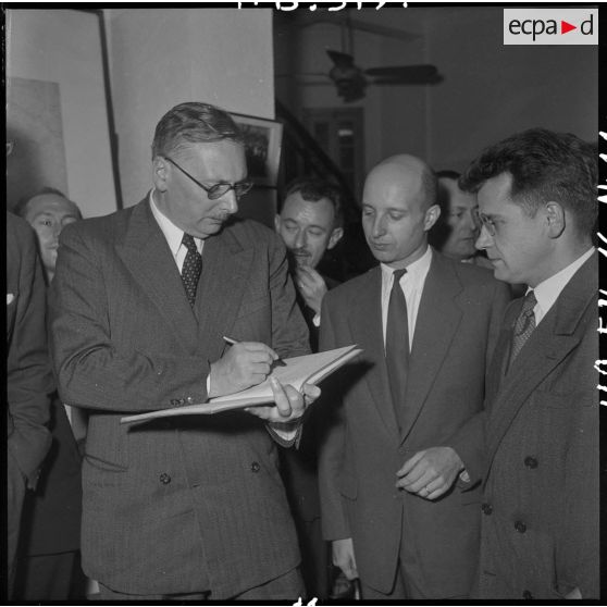 M. Pleven, ministre de la Défense nationale, signe le livre d'or du camp de presse d'Hanoï.