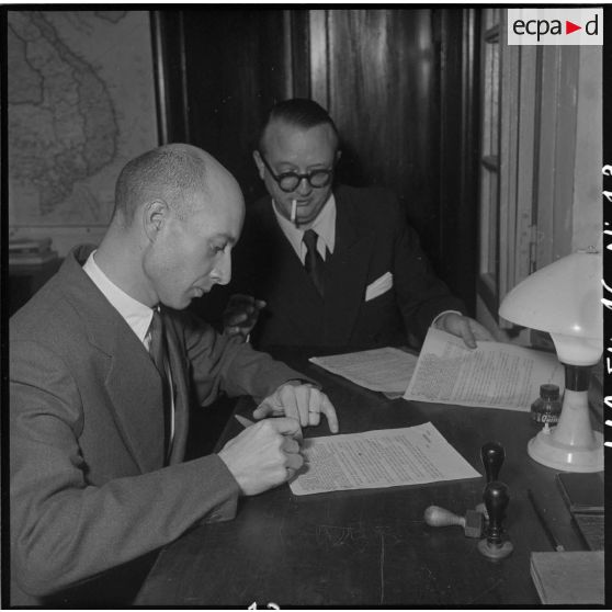 Un officier censeur contrôle les informations notées par les journalistes au cours de la conférence donnée au camp de presse d'Hanoï par M. Pleven, ministre de la Défense nationale.