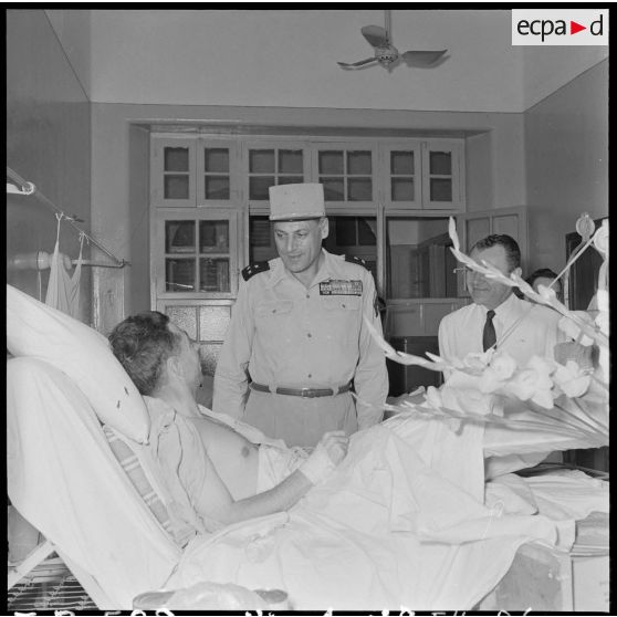 Le général Cogny, commandant en chef des FTNV (forces terrestres du Nord-Vietnam), s'entretient avec un soldat blessé à Diên Biên Phu et rapatrié à l'hôpital militaire Lanessan.