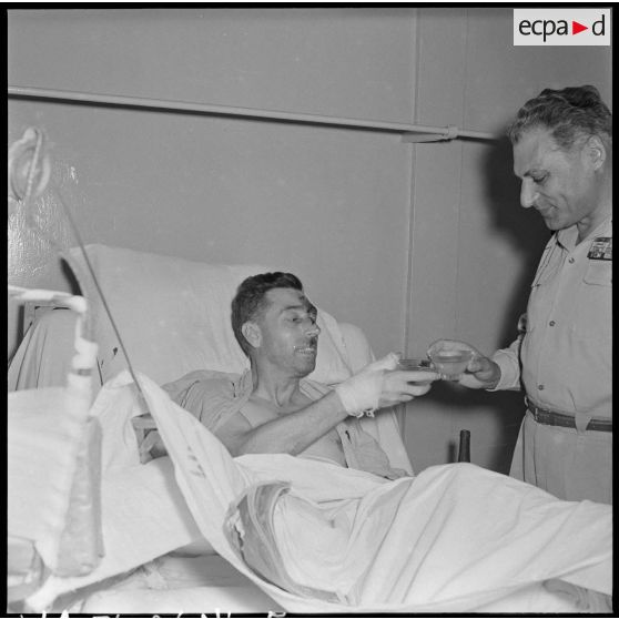 Le général Cogny, commandant en chef des FTNV (forces terrestres du Nord-Vietnam), trinque avec un capitaine blessé à Diên Biên Phu et rapatrié à l'hôpital militaire Lanessan.