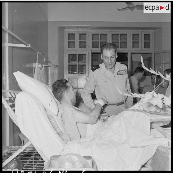 Le général Cogny, commandant en chef des FTNV (forces terrestres du Nord-Vietnam), s'entretient avec un capitaine blessé à Diên Biên Phu et rapatrié à l'hôpital militaire Lanessan.