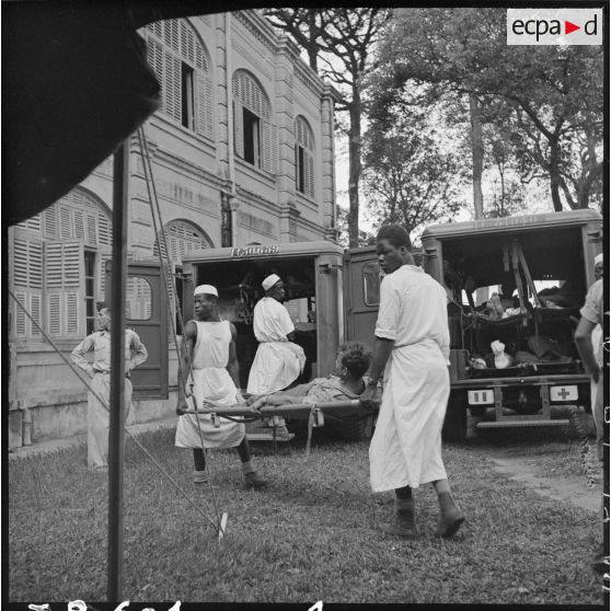 Les brancardiers transportent les derniers blessés évacués de Diên Biên Phu dans la tente de triage.