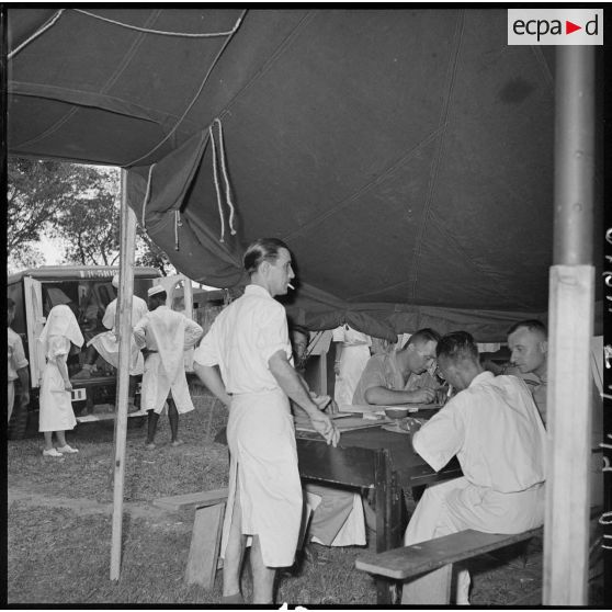 Personnel médical et administratif sous une tente de triage installée à l'hôpital militaire Lanessan.