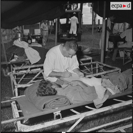 Les derniers blessés, évacués de Diên Biên Phu, reçoivent les premiers soins dans une tente de triage installée à l'hôpital militaire Lanessan.	