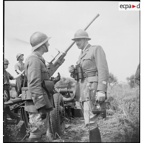 Lors d'une école à feu du 411e RAAA  (régiment d'artillerie antiaérienne) de la DMC (division de marche de Constantine), un capitaine et un lieutenant discutent devant un canon de 40 mm Bofors.