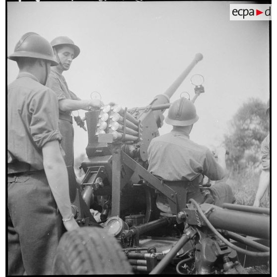 Lors d'une école à feu du 411e RAAA  (régiment d'artillerie antiaérienne) de la DMC (division de marche de Constantine), des artilleurs chargent un canon de 40 mm Bofors.