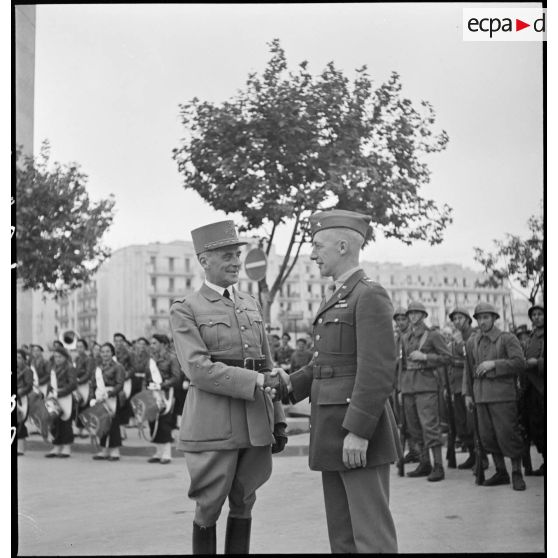 Lors de la cérémonie de remise des chaînes de montage de matériels, dans le cadre du réarmement de l'armée française par les Américains, le brigadier américain, Ernest A. Suttles, responsable de la mise en place des chantiers d'assemblage d'Alger, et le général d'armée René Prioux, major général des forces terrestres et aériennes, échangent une poignée de mains.