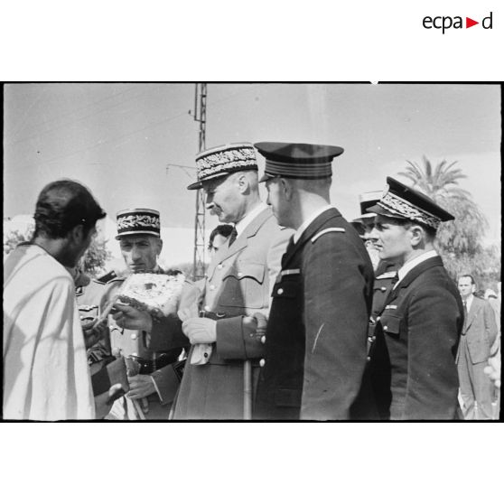 Le général d'armée Henri Giraud, commandant en chef civil et militaire, examine un objet artisanal produit à Bou Saada que lui présente un habitant.