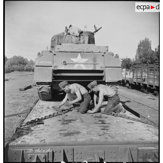 En gare de Boufarik, des soldats français arriment sur un wagon porte-chars un char moyen sherman M4 A4 américain, destiné au 5e RCA (régiment de chasseurs d'Afrique) de la 1re DB (division blindée).