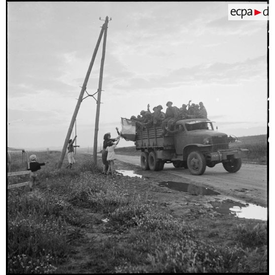 Aux portes de Bizerte, la population civile salue l'arrivée de soldats du CFA (Corps franc d'Afrique), embarqués à bord d'un GMC.