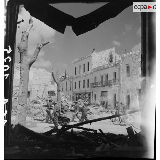 Des civils rentrent dans Bizerte en ruine sous la protection de soldats du CFA (Corps franc d'Afrique).