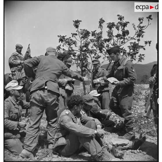 Un officier du CFA (Corps franc d'Afrique) rend leurs livrets matricules à des prisonniers allemands avant leur interrogatoire.