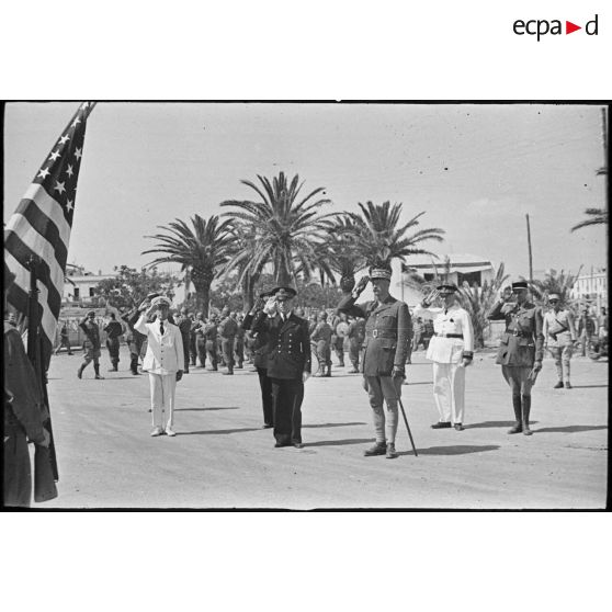 Le général d'armée Henri Giraud, commandant en chef civil et militaire, et le vice-amiral Marcel Leclerc, commandant la Marine en Tunisie, saluent le drapeau des Etats-Unis lors d'une cérémonie et d'un défilé des troupes.