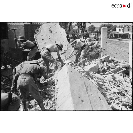 Des soldats recherchent de victimes parmi les ruines des habitations situées à proximité de la gare ferroviaire de Maison-Carrée, suite à l'explosion d'un wagon de munitions le 4 juillet 1943.