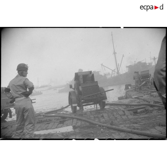 Sur un quai du port d'Alger, des pompiers utilisent des remorques de sécurité incendie pour maîtriser le feu à bord d'un navire pétrolier.