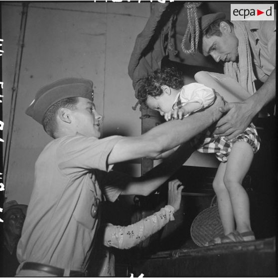 Des militaires du CEFEO (Corps expéditionnaire français en Extrême-Orient ) aident un enfant réfugié à descendre d'un camion.