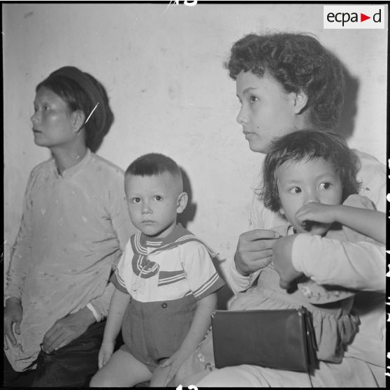 Deux femmes et des enfants attendent d'être pesés pour pouvoir monter dans l'avion du pont aérien.