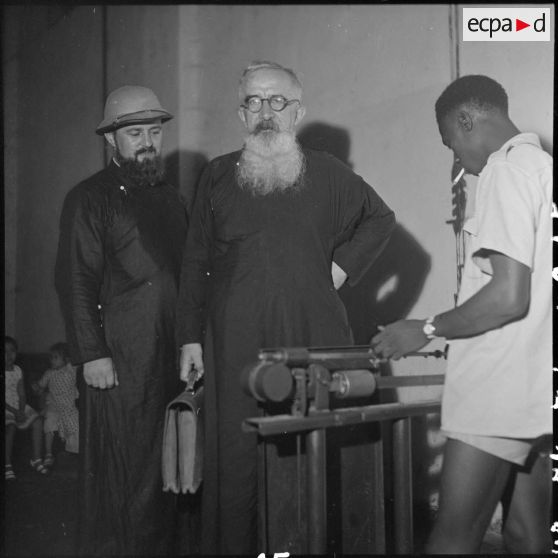 Portrait de deux prêtres français pesés à Bach Mai avant de monter à bord d'un avion du pont aérien.
